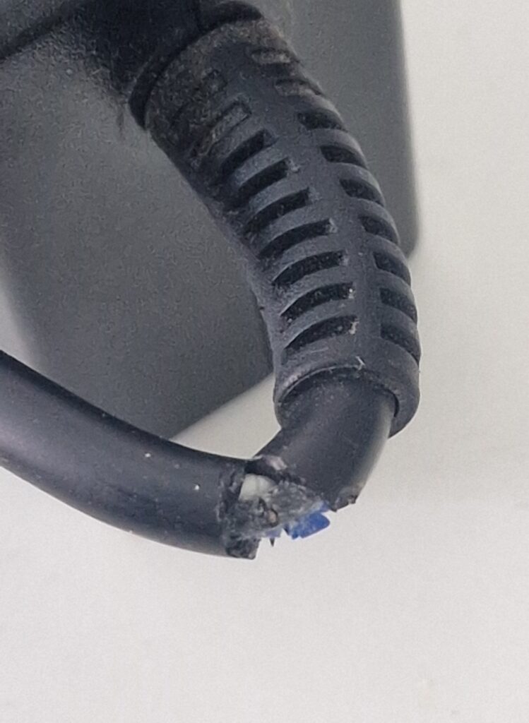 cargador de portátil con cable desgastado que puede provocar un cortocircuito