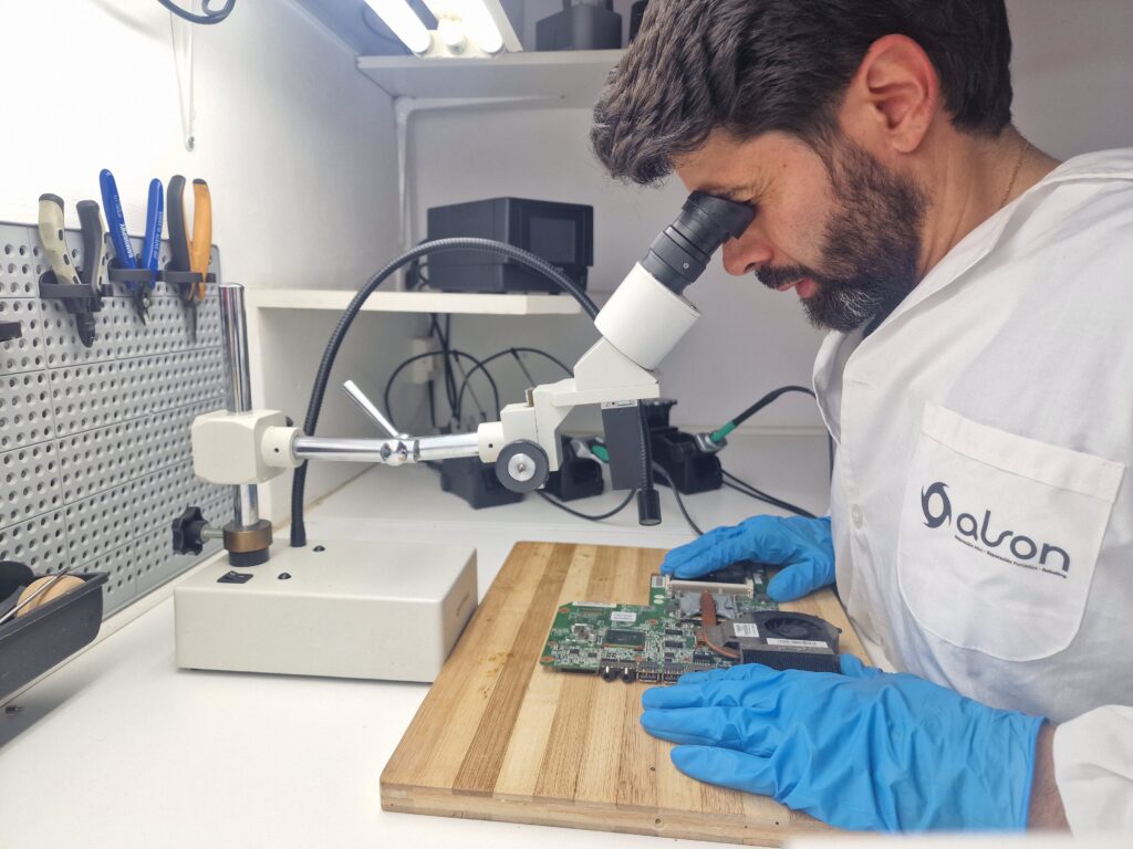 técnico revisando placa base de portátil con microscopio